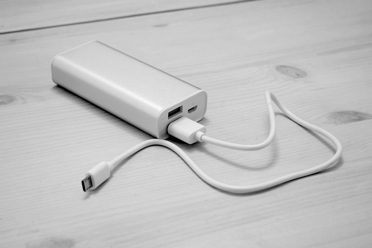 White compact power bank connected to a USB cable on a wooden table (representative photo, not the exact product)