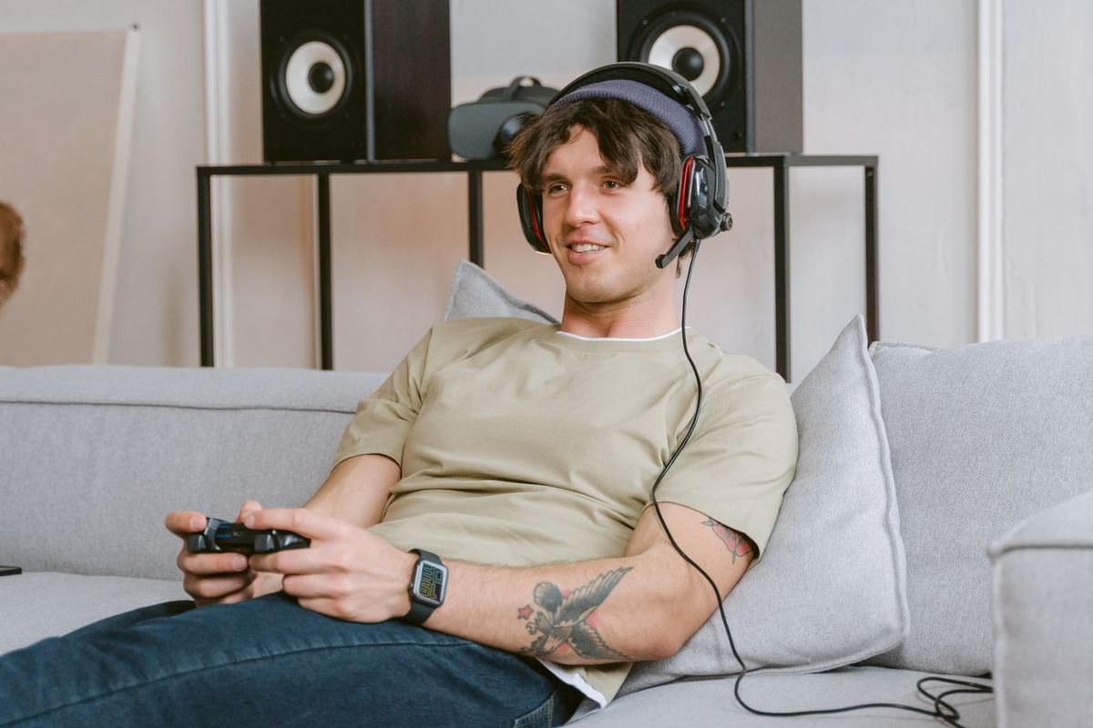 Young man relaxing on the couch playing video games with a headset
