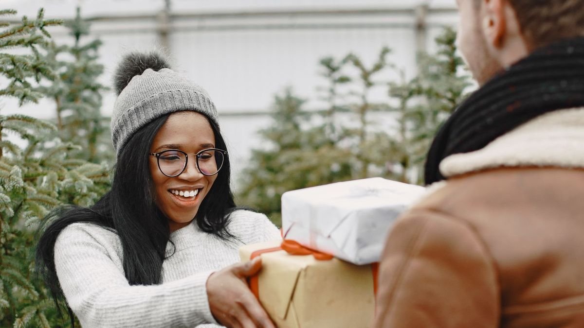 Couple happily exchanging Christmas gifts outdoors