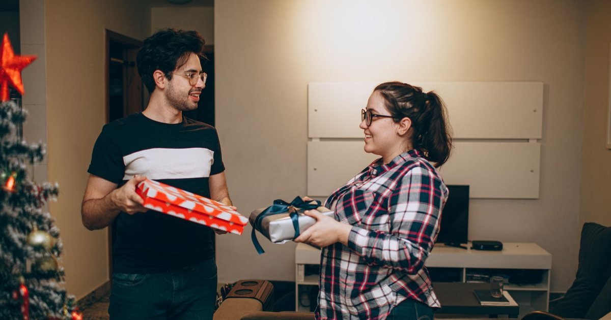 Couple exchanging Christmas gifts in a cozy living room