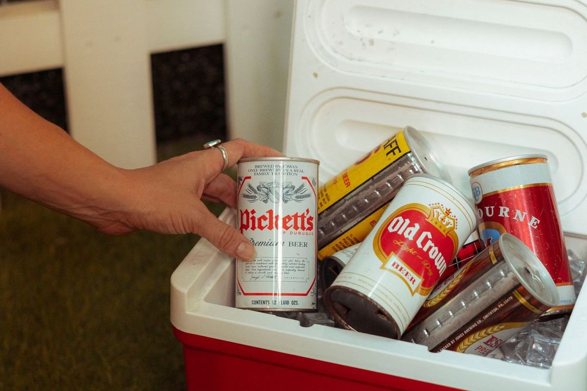 Hand reaching for a drink can in an outdoor cooler (representative photo, not the exact product)