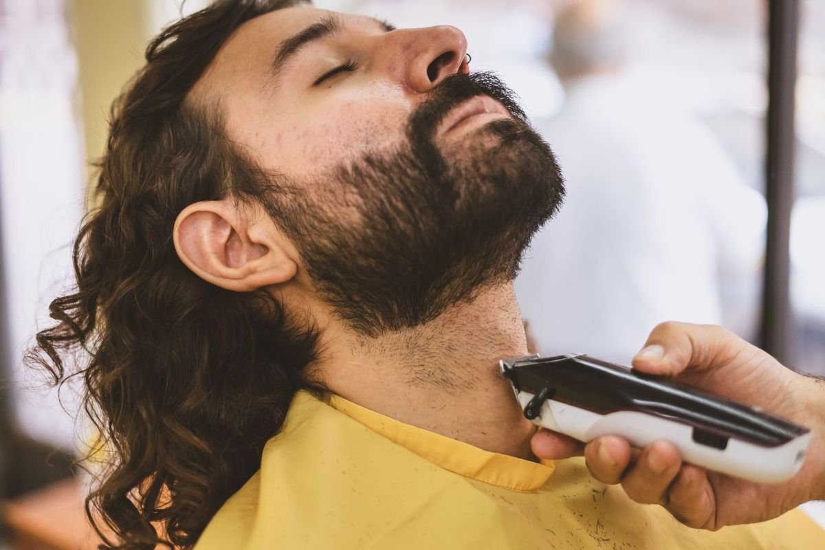 Barber trimming a man's beard with an electric clipper (representative photo, not the exact product)