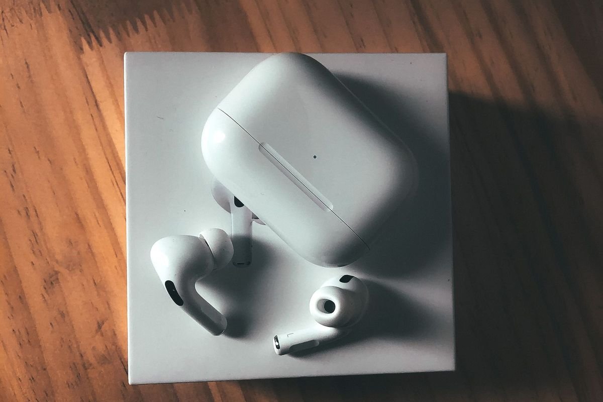 White wireless earbuds with charging case on a wooden table (representative photo, not the exact product)
