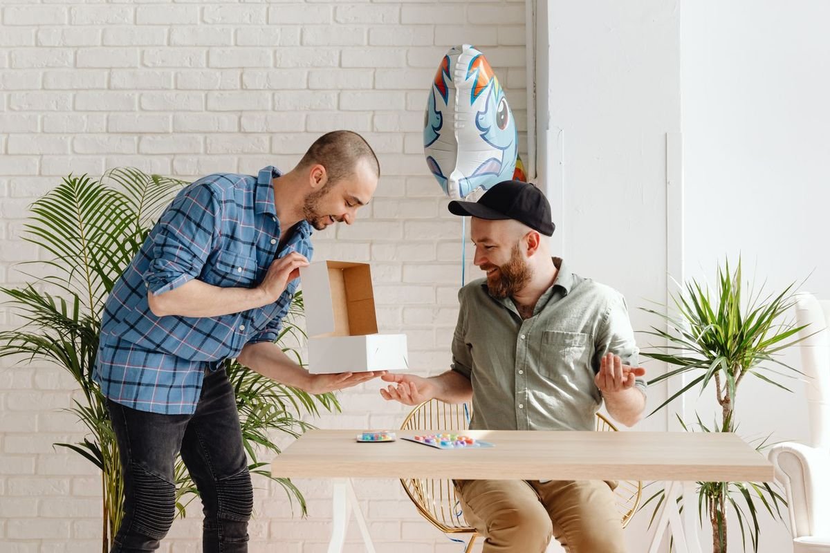 Two men exchanging a gift box in a bright living room
