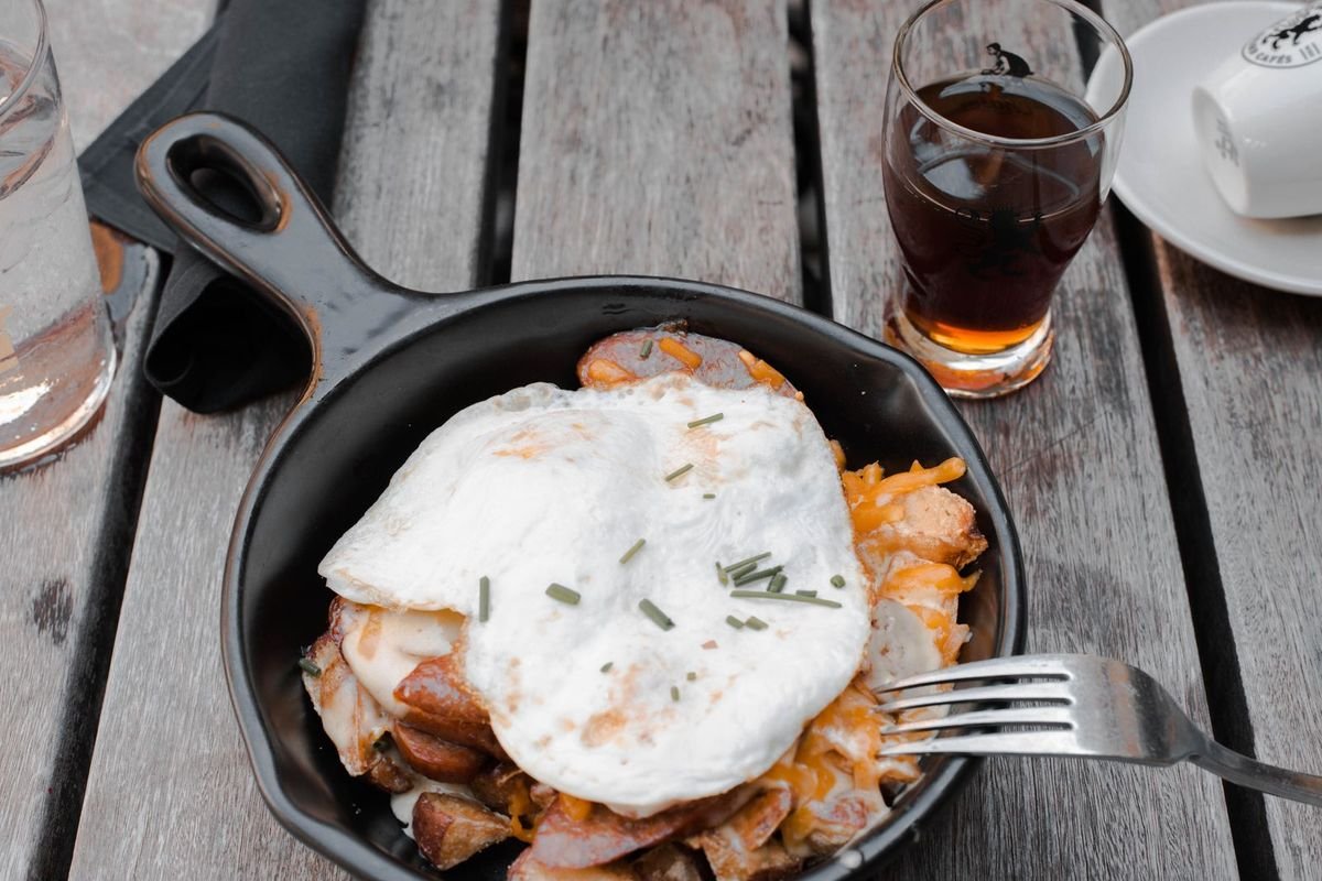 Cast iron skillet with fried eggs and meat on a rustic wooden table (representative photo, not the exact product)