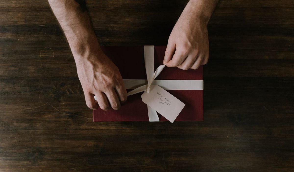 Hands tying a ribbon on a wrapped gift box