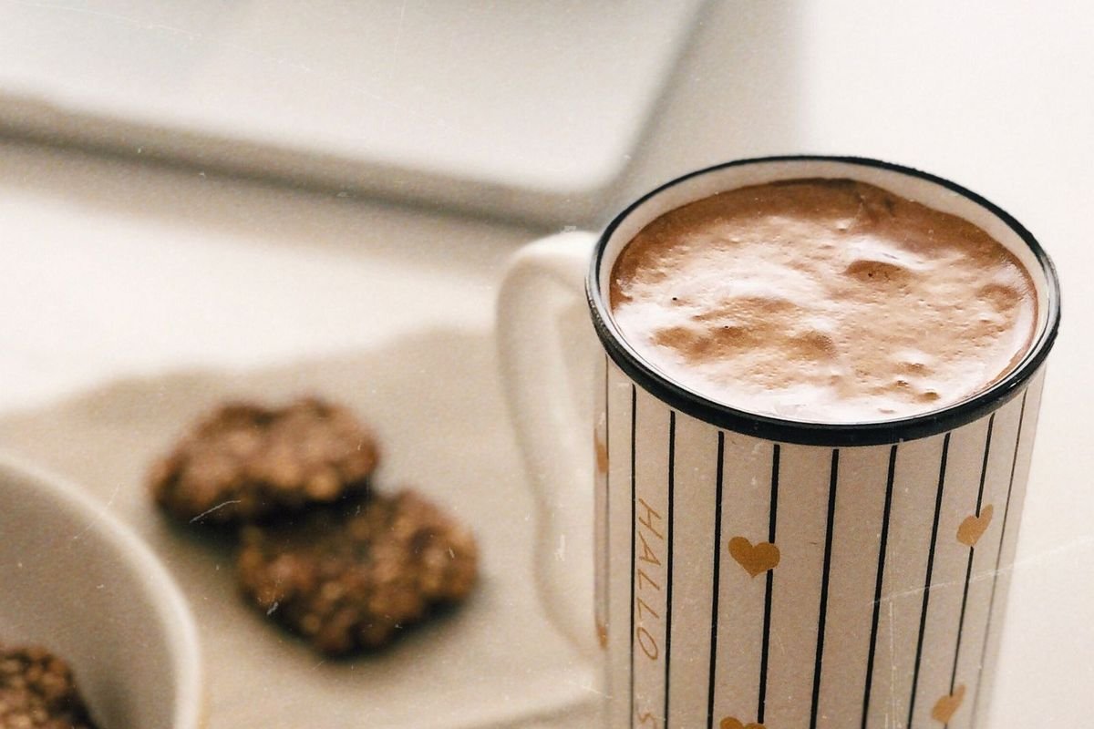 White ceramic mug with coffee beside a laptop (representative photo, not the exact product)