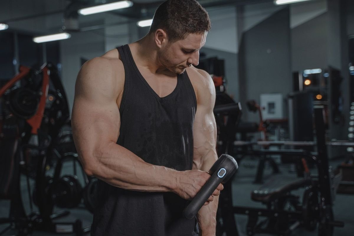 Man using a massage gun in a gym (representative photo, not the exact product)