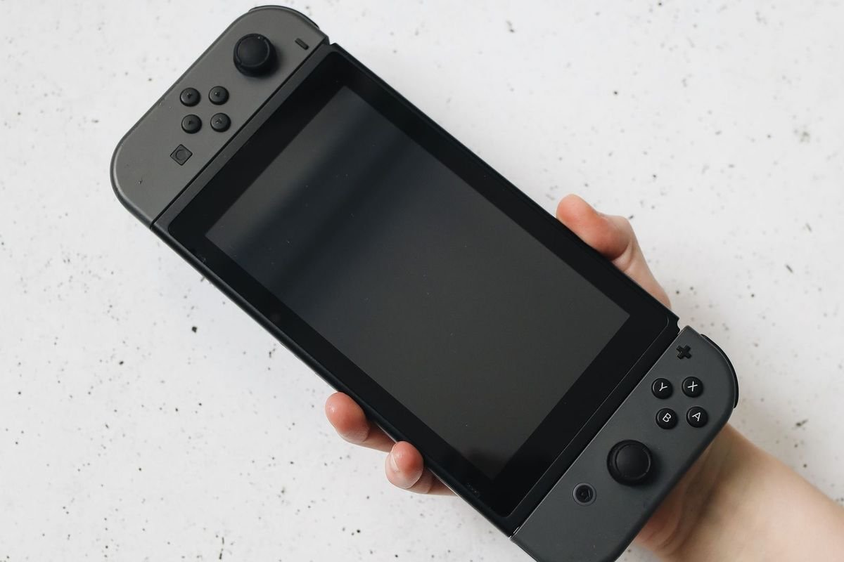Hand holding a handheld game console (representative photo, not the exact product)