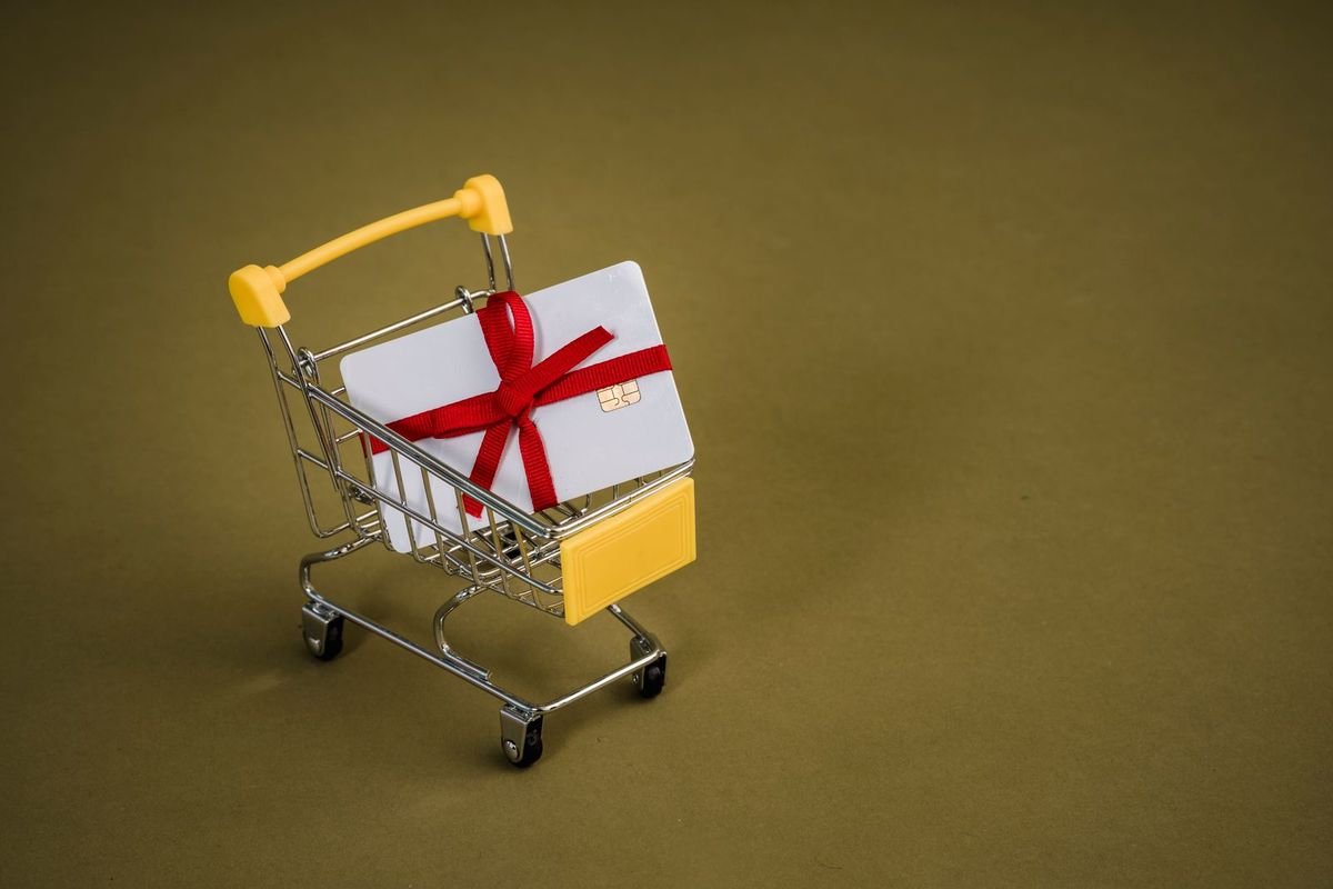 Gift card with a red ribbon in a miniature shopping cart (representative photo, not the exact product)