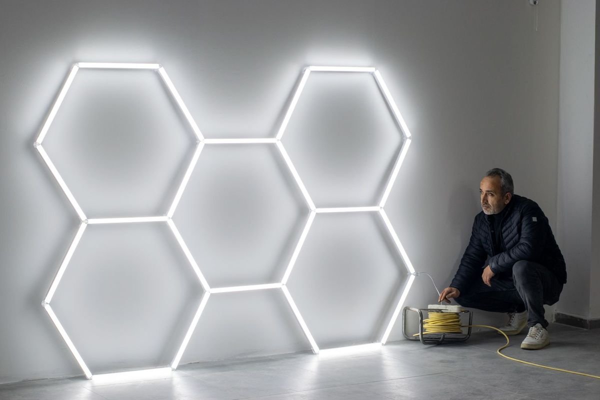 Man installing hexagon LED wall lights (representative photo, not the exact product)