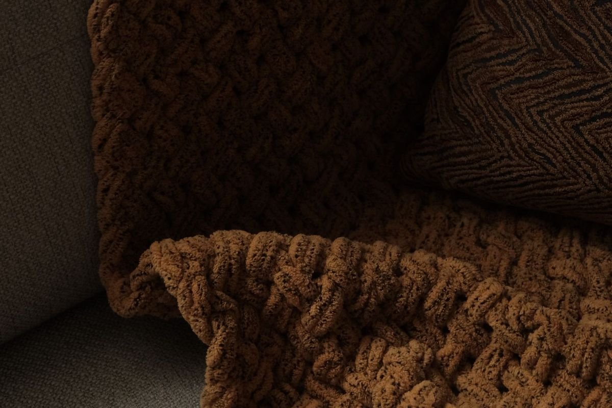 Brown knit blanket draped over a beige sofa (representative photo, not the exact product)