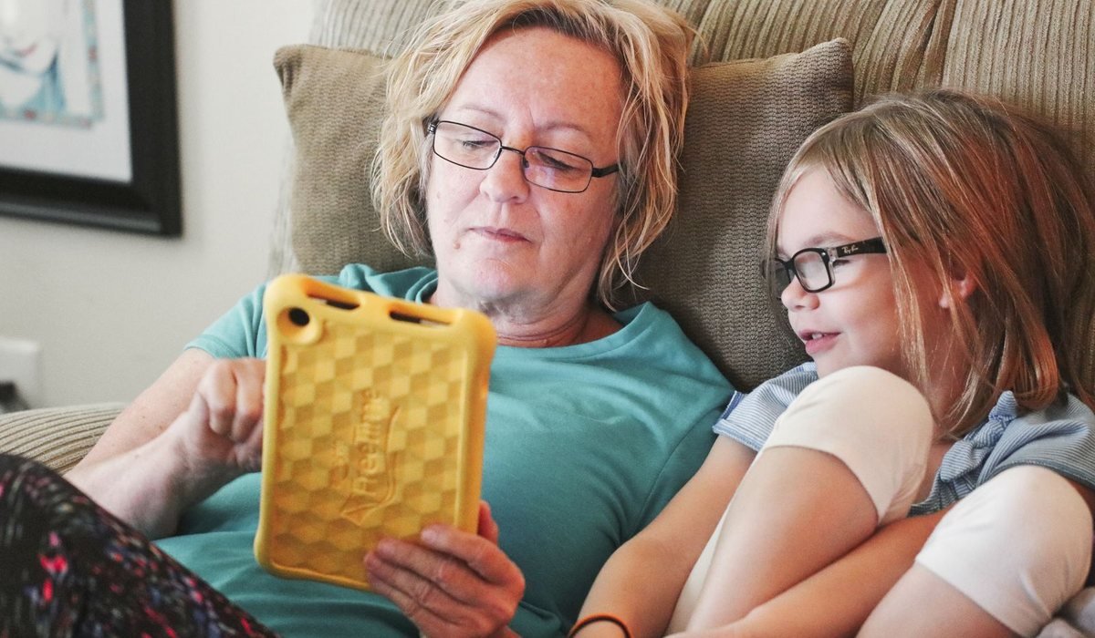Grandmother and granddaughter relaxing on the couch with a tablet