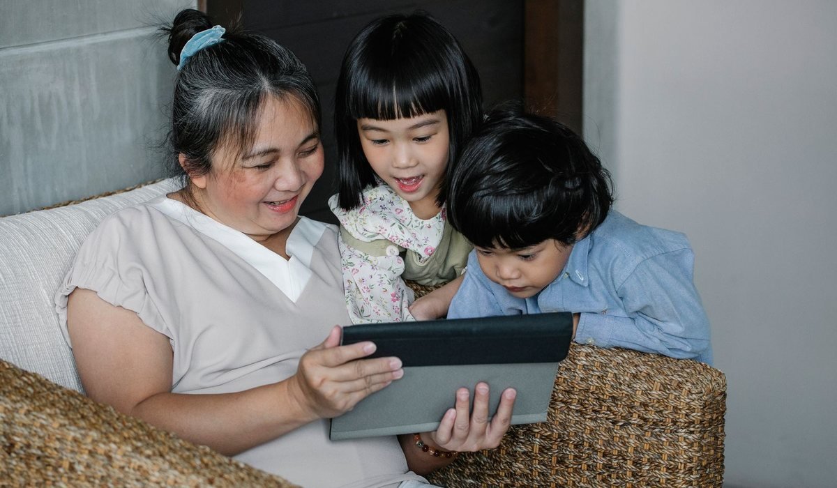 Grandmother showing a tablet to her two grandchildren