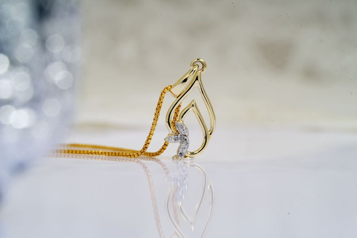 Gold pendant on a chain on a reflective table (representative photo, not the exact product)