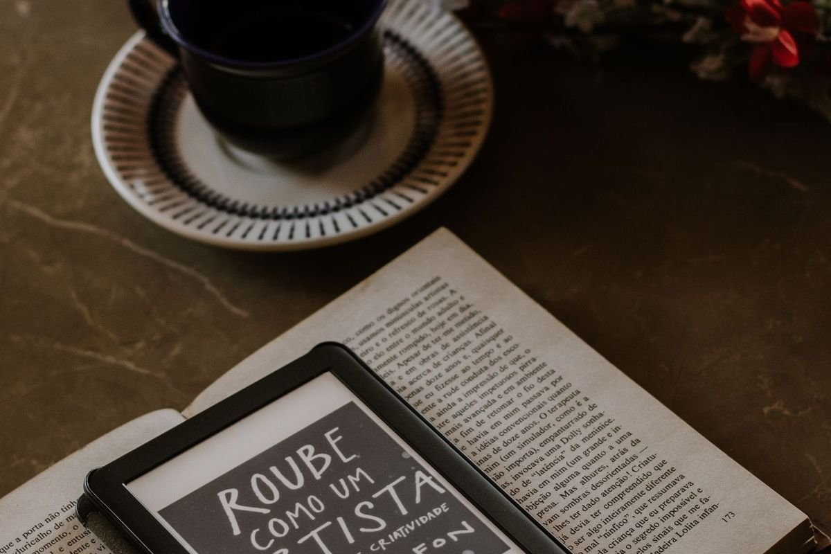 E-reader on an open book beside coffee and flowers (representative photo, not the exact product)