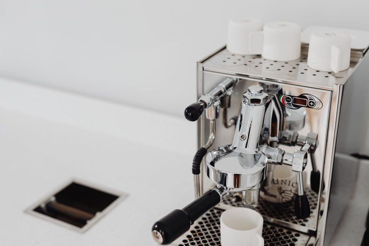 Polished espresso machine on a white counter (representative photo, not the exact product)