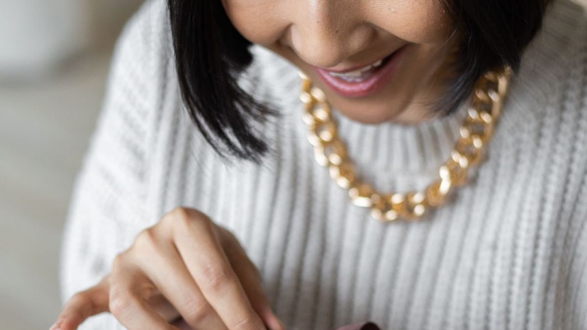 Happy woman in a cozy sweater opening a wrapped gift box