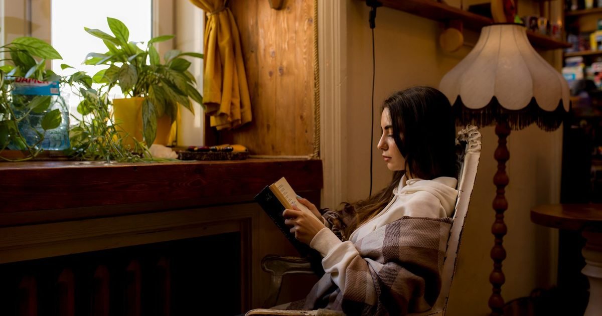 Woman reading a book in a cozy, lamp-lit room