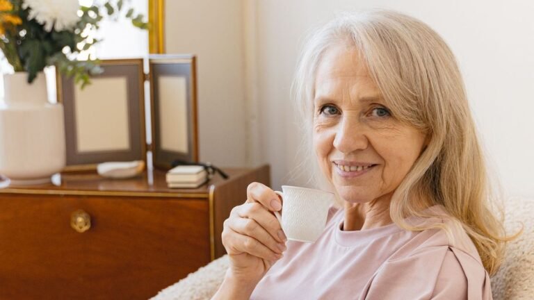 Smiling older woman relaxing in an armchair with a cup of tea