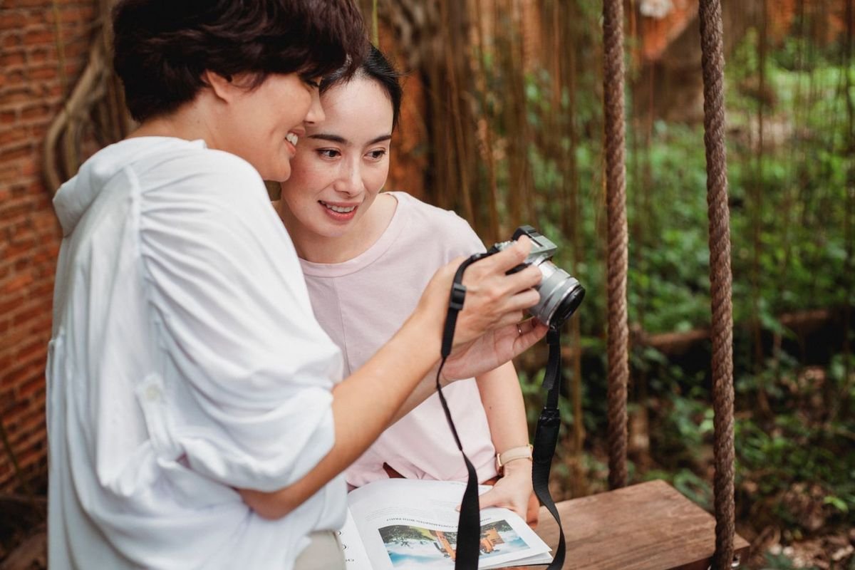 Two women smiling as they look through photos on a camera together