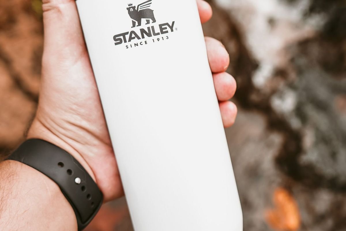 Hand holding a white insulated tumbler outdoors (representative photo, not the exact product)