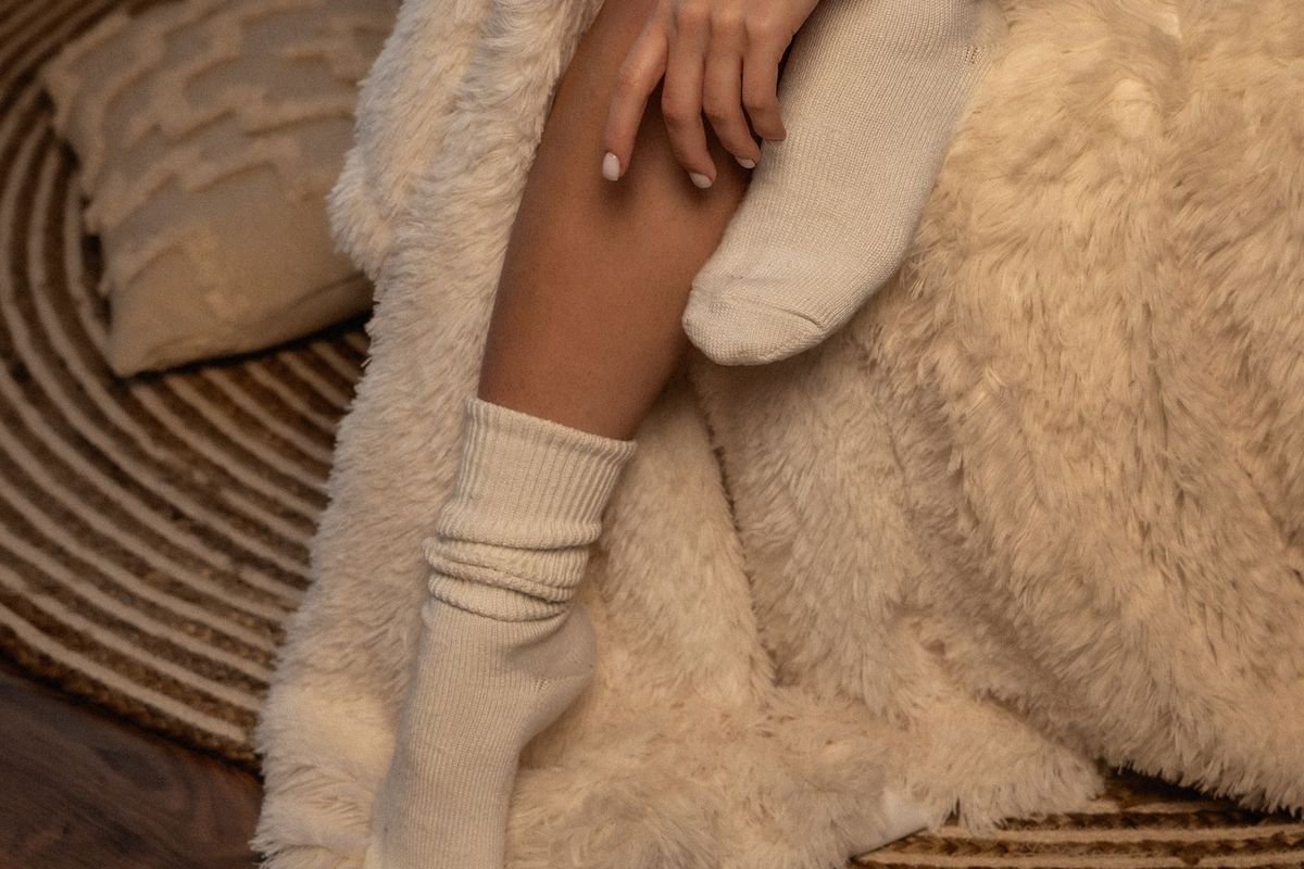 Woman in warm socks sitting on a bed (representative photo, not the exact product)