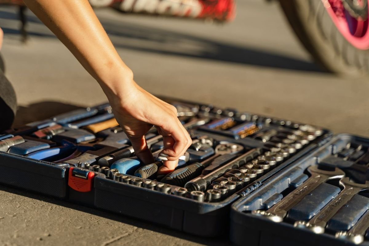 Hand picking a tool from an organized toolbox in sunlight