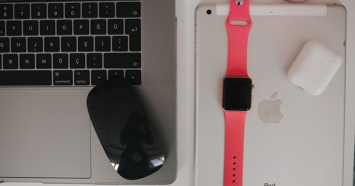 Laptop, wireless mouse, smartwatch, earbuds and tablet on a desk