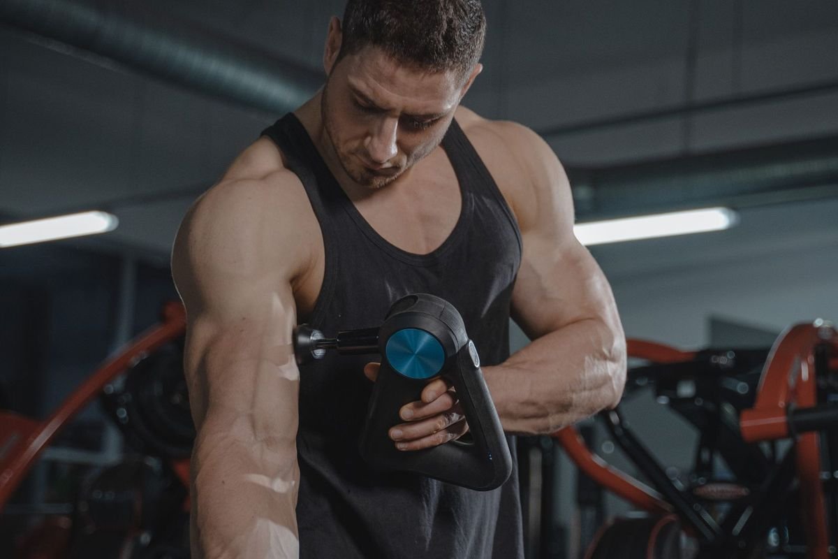 Man using a massage gun in a gym (representative photo, not the exact product)