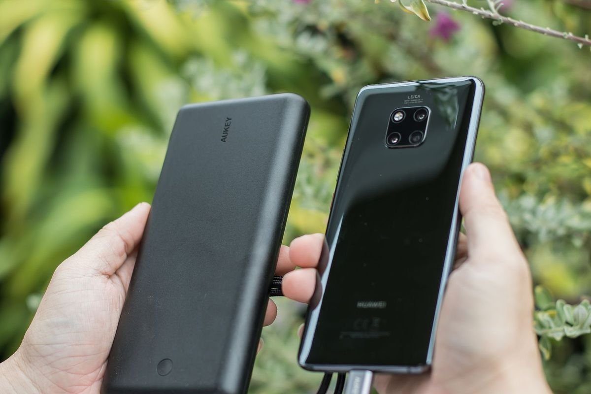 Person with a smartphone and power bank outdoors (representative photo, not the exact product)