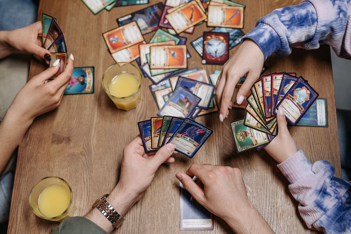 Hands holding playing cards at a table (representative photo, not the exact product)