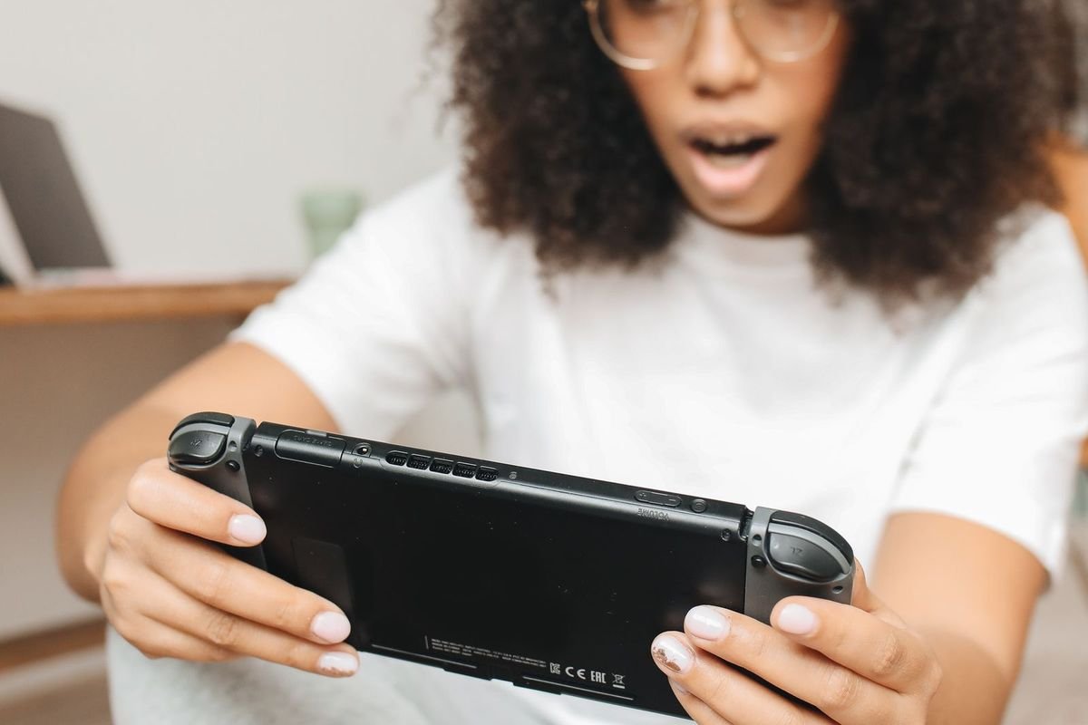 Woman playing a handheld game console (representative photo, not the exact product)