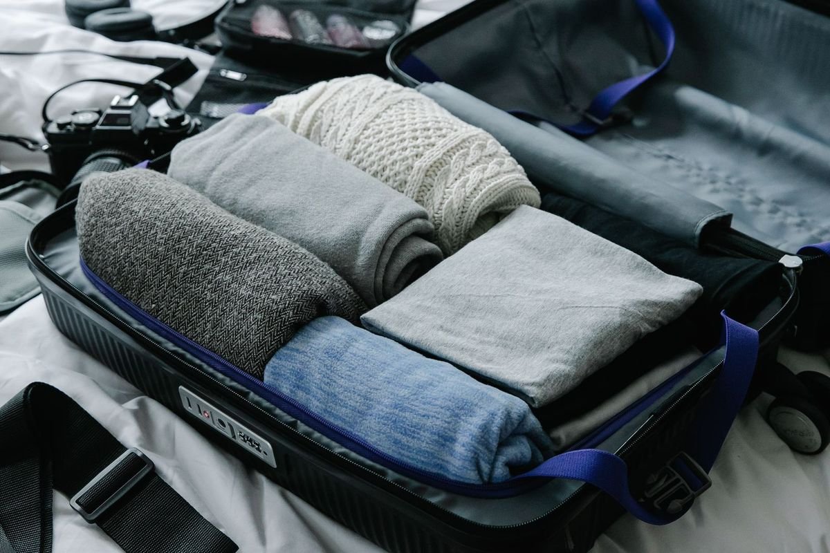 Open suitcase with neatly folded clothes on a bed before a trip (representative photo, not the exact product)