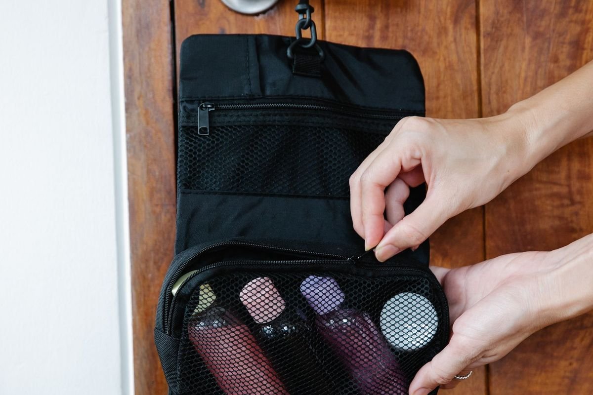 Hanging toiletry bag filled with cosmetics on a wooden door handle (representative photo, not the exact product)