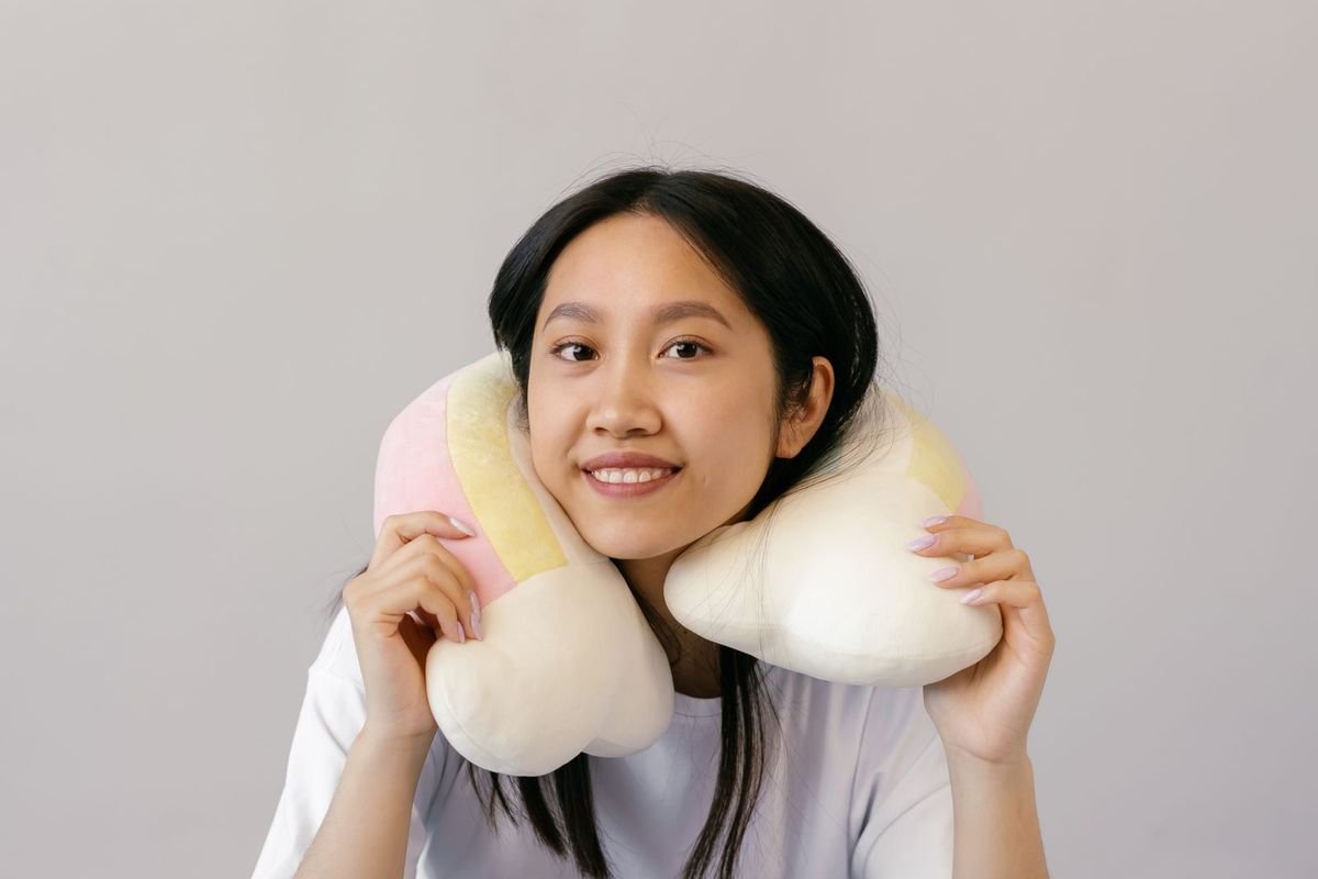 Smiling woman sitting on the floor wearing a plush neck pillow (representative photo, not the exact product)