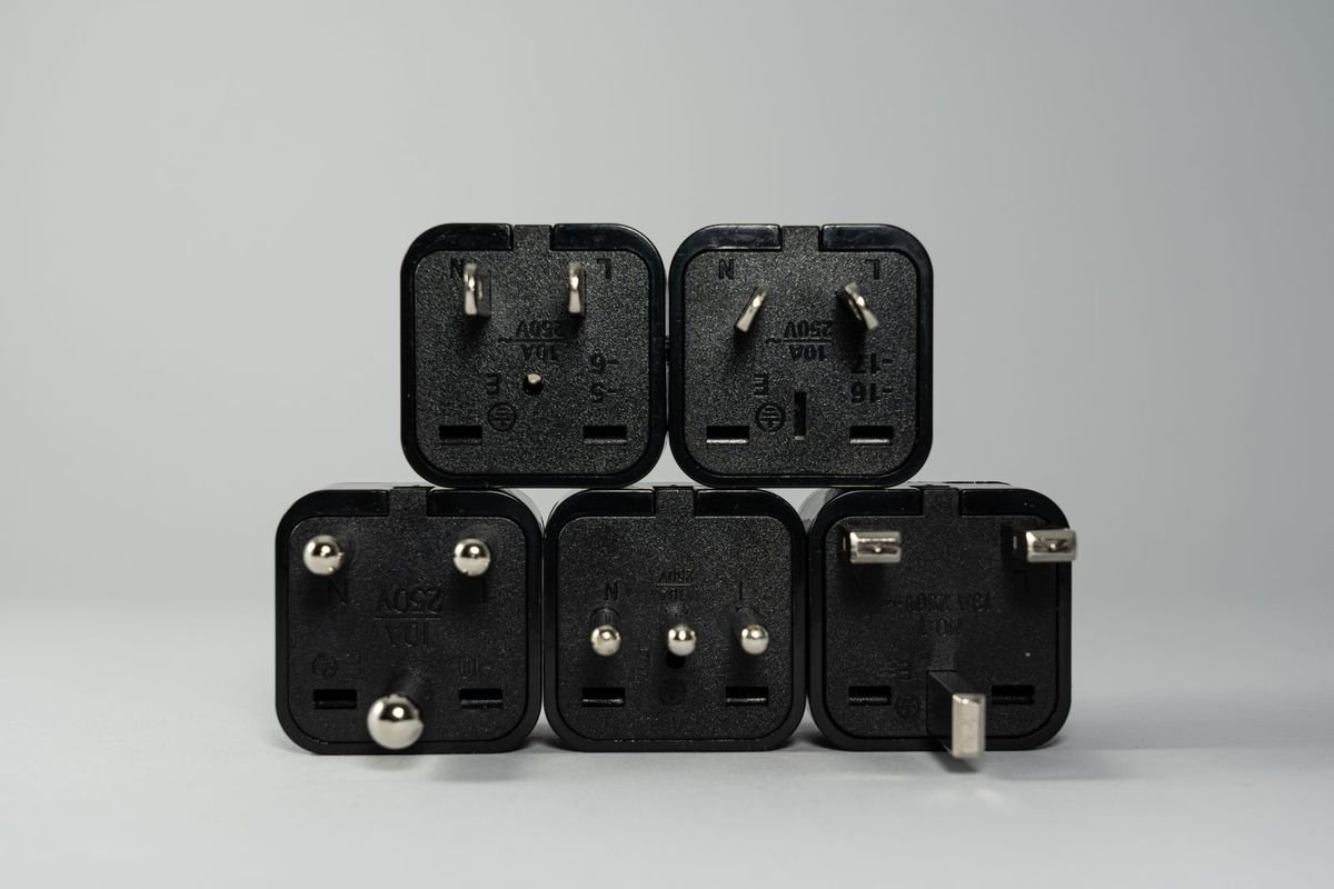 Several black international plug adapters stacked on a light background (representative photo, not the exact product)