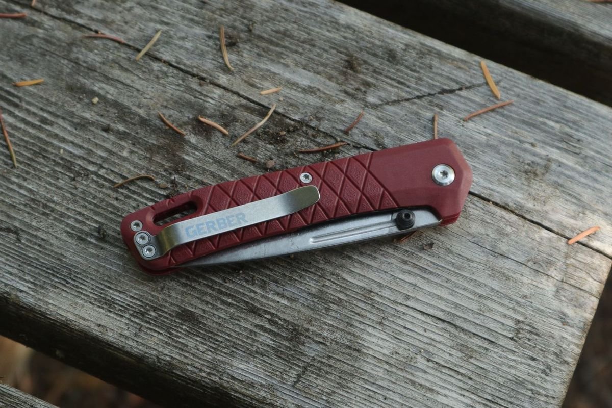 Red pocket knife on a wooden surface (representative photo, not the exact product)