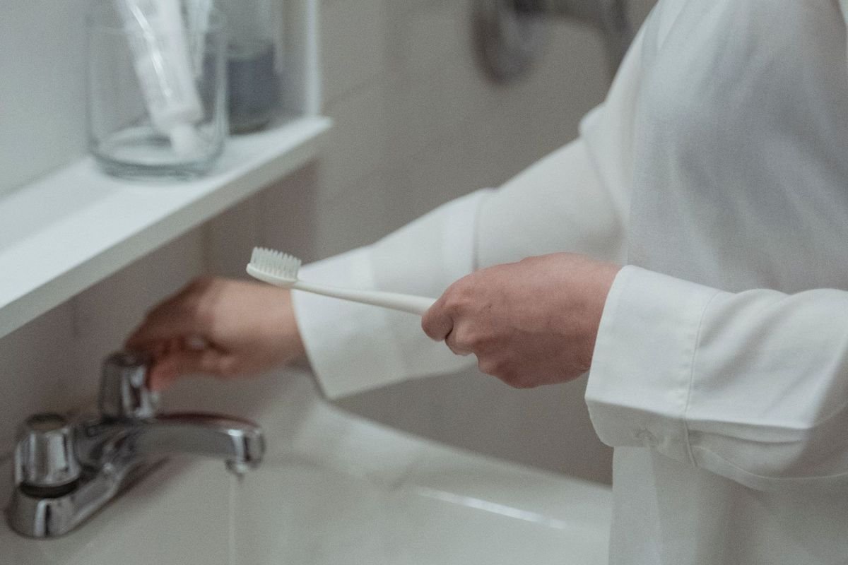 Woman brushing teeth in a white bathroom (representative photo, not the exact product)