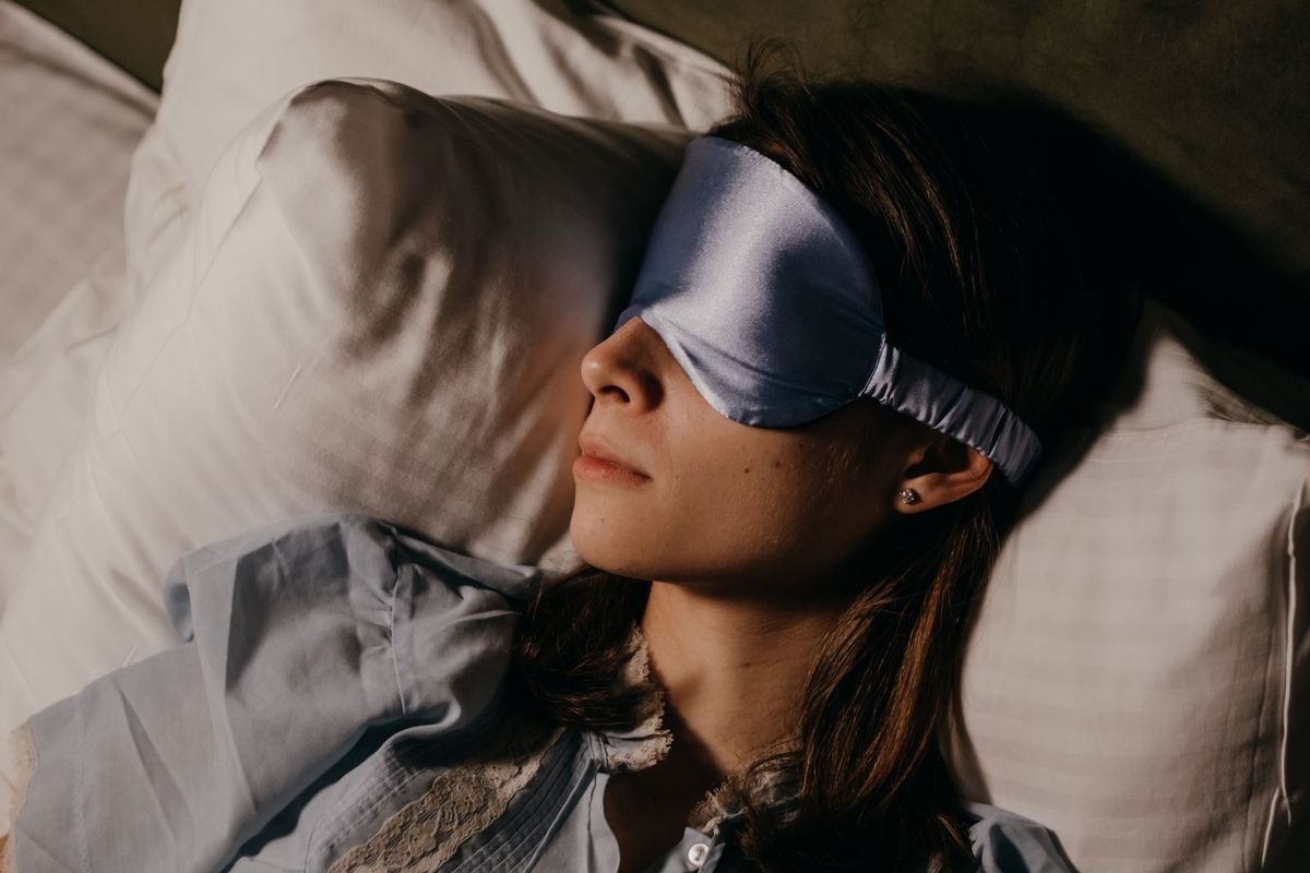 Woman asleep wearing an eye mask (representative photo, not the exact product)