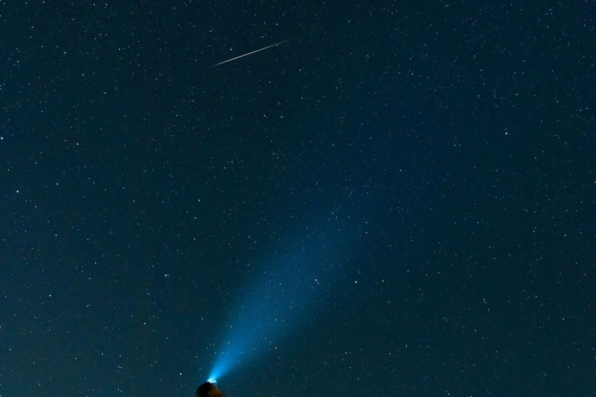 Hiker with a light looking at a starry night sky (representative photo, not the exact product)