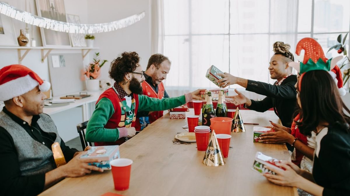 Friends exchanging Christmas gifts around a festive party table