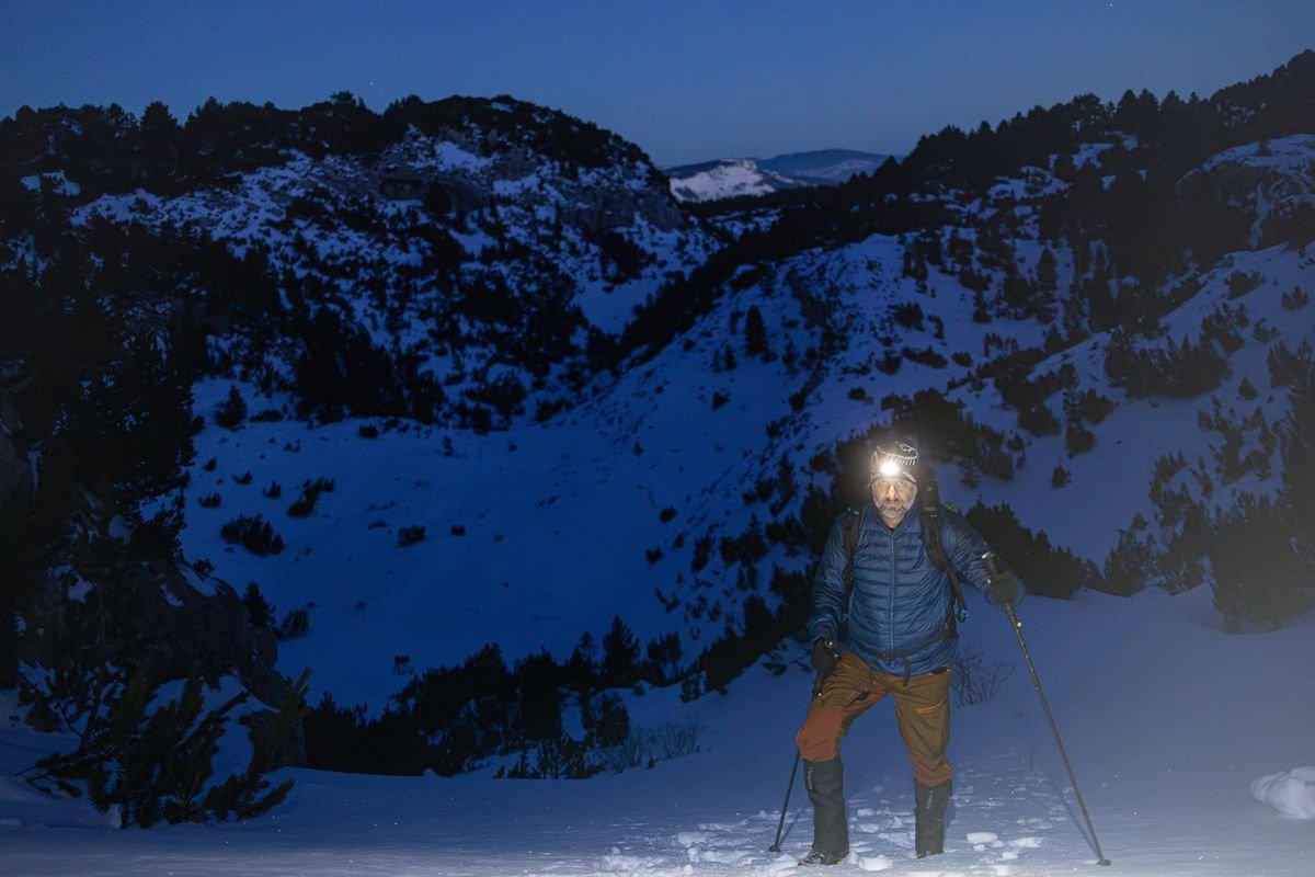 Hiker using a headlamp on a mountain at night (representative photo, not the exact product)
