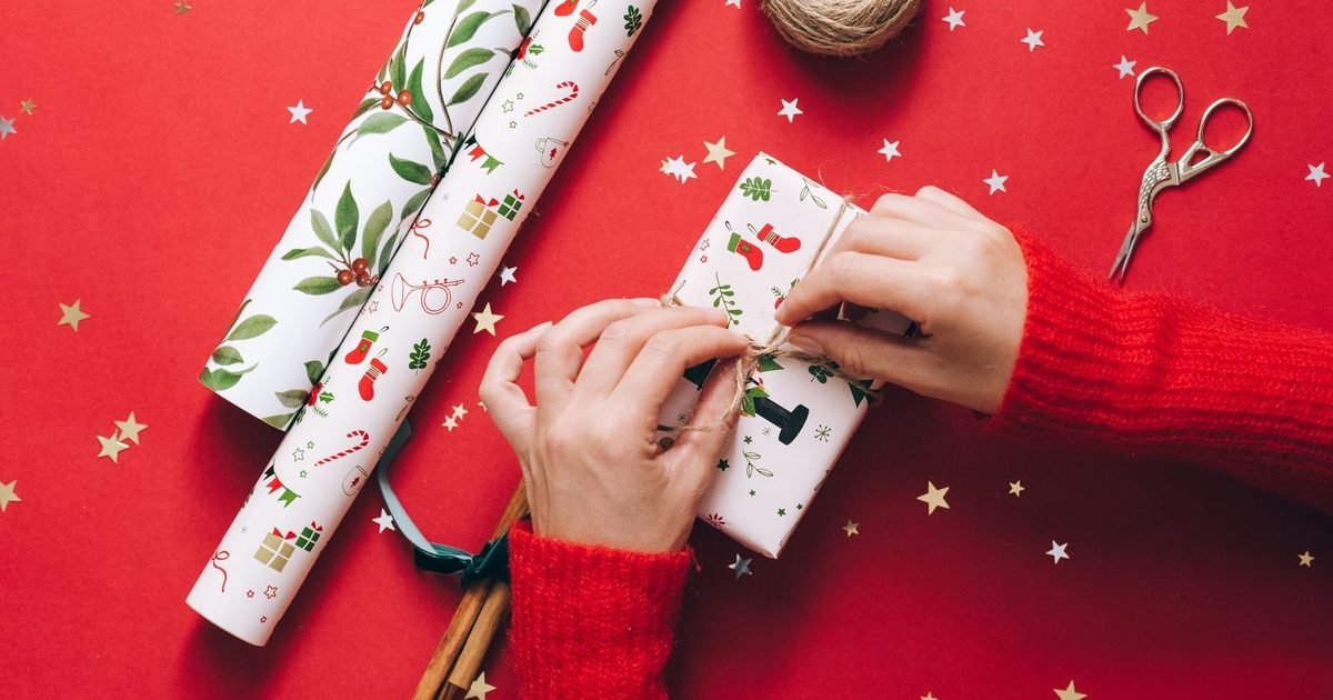 Hands wrapping Christmas presents with festive paper and twine