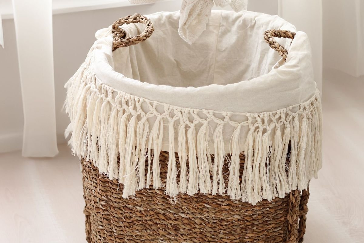 Hand placing laundry into a wicker basket (representative photo, not the exact product)