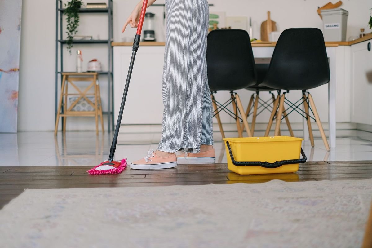 Person mopping a wooden floor with a bucket (representative photo, not the exact product)