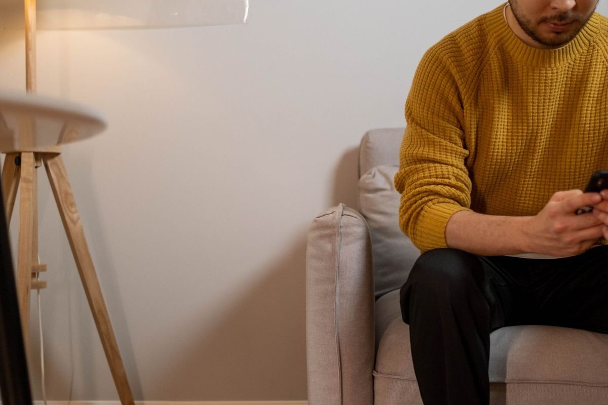 Man in an armchair with a robot vacuum on the floor (representative photo, not the exact product)