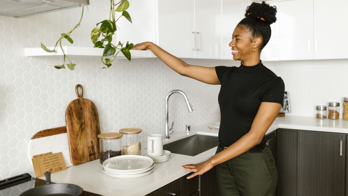 Smiling woman organizing a bright white kitchen